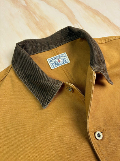 Close-up of a Khaki cotton canvas Chore coat with a dark brown corduroy collar, showing the interior neck label.