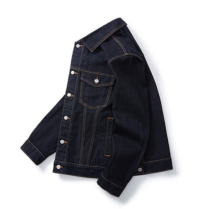 A dark indigo type 3 selvedge denim jacket with contrasting orange stitching and silver snap buttons, laid on it's side on a flat on a white background.