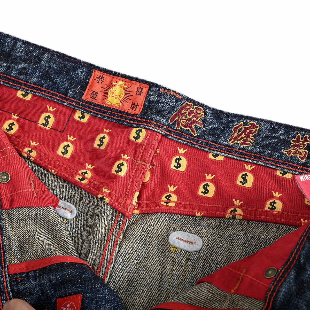 Close-up of the interior waistband and lining of a pair of jeans. The waistband is dark blue denim with red embroidered Chinese characters and a small red label.