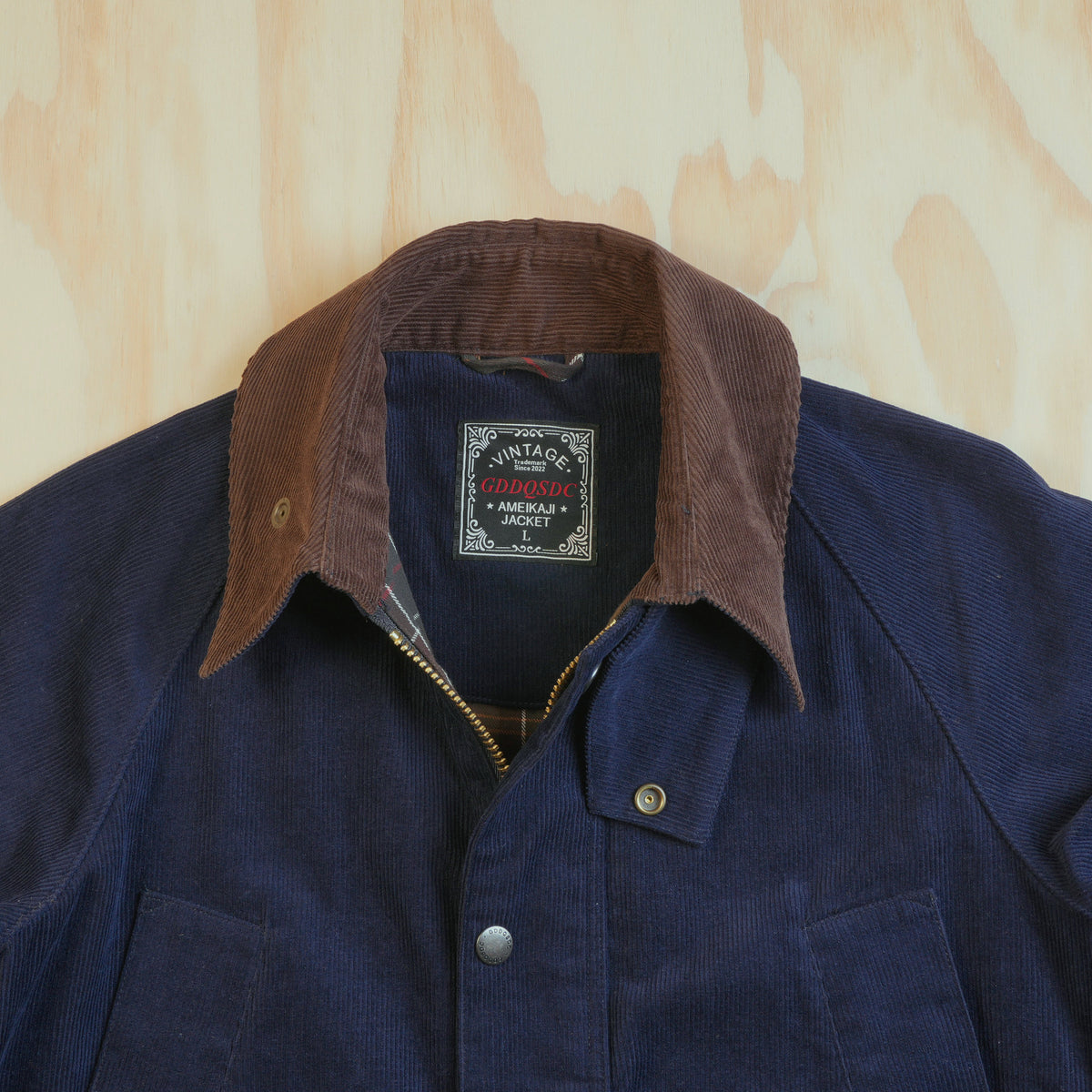Close-up of the contrasting brown corduroy collar, zip and snap-fastened throat tab on the navy hunting jacket.